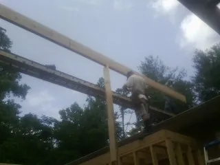 Carpenter setting a ridge beam over a new addition frame — Ice Dam Removal by Roofing Brothers in Ravena
