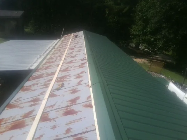 Old rusted panels beside newly installed green metal roofing — Wind Damage Roof Repair by Roofing Brothers in Ravena