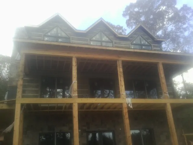 Dormers and porch framing on a large log home under construction — Roof Coating work by our crew in Ravena