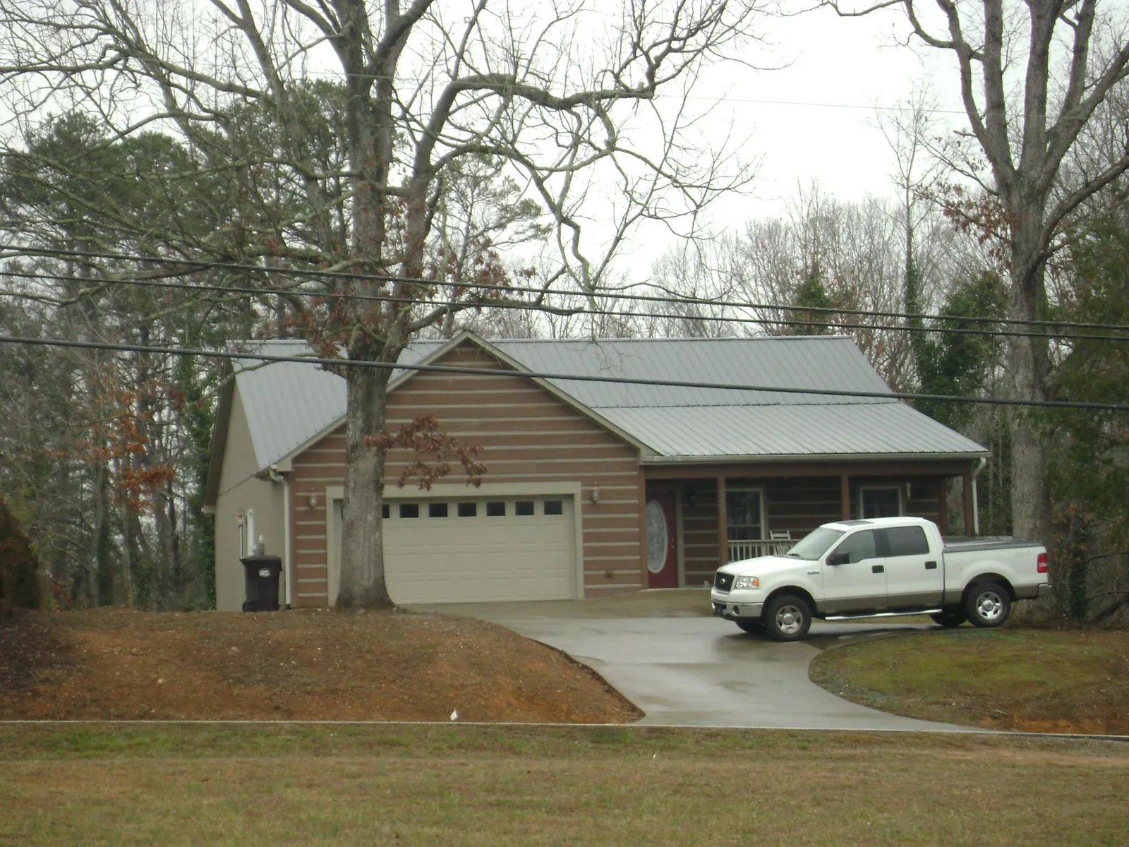 Gray metal roof on a log sided house with an attached two car garage in Ravena