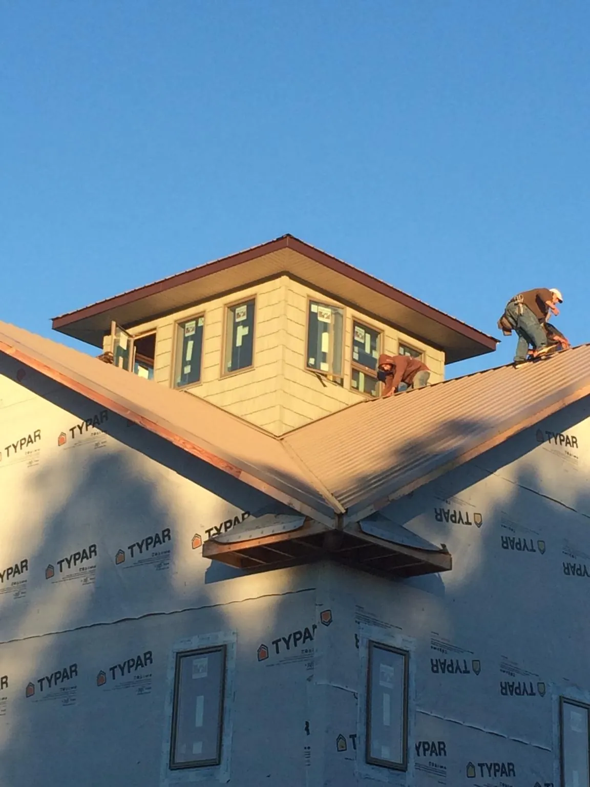 Roofers working around a rooftop cupola on a new metal roof at sunset — Roof Waterproofing in Ravena by Roofing Brothers